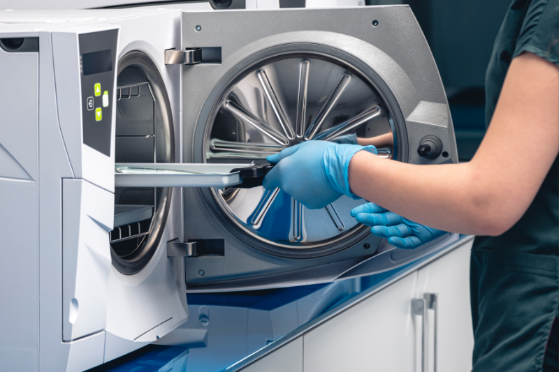 Nhân viên y tế tại Nha khoa Ace Smile đang đưa khay dụng cụ vào nồi hấp tiệt trùng Autoclave để chuẩn bị cho chu trình vô khuẩn.